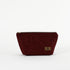 A burgundy floral damask makeup bag with a zip closure and a small brand tag attached to the front named after Alaney 