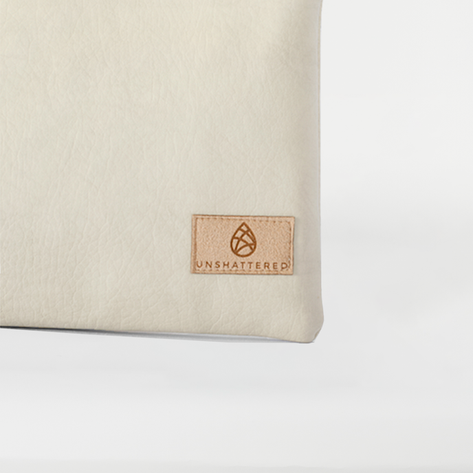 A tan label on a creamy taupe large zip pouch named after Alecia 