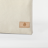 A tan label on a creamy taupe large zip pouch named after Alecia 