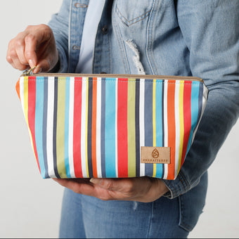 Person holding a colorful striped makeup bag  with a plain background named after Alex 