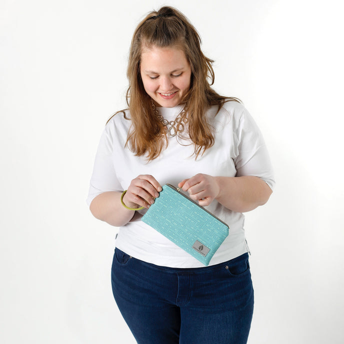 Woman holding a teal wristlet bag against a white background named after Alicia 