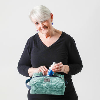 A woman holding a blue geometric design toiletry wearing a black shirt named after Alisa