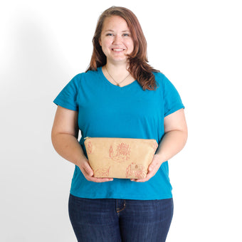 Woman holding a beige makeup kit with red embroidered flowers against a plain background
