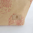 Beige fabric with red floral patterns and 'Unshattered' brand logo on a white background