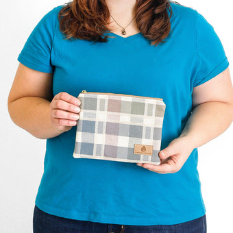 A woman holding a pastel checkered zip pouch named after Alyzaah 