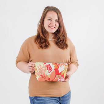 A woman holding a summer floral pattern makeup bag with a zip closure named after Amiya.