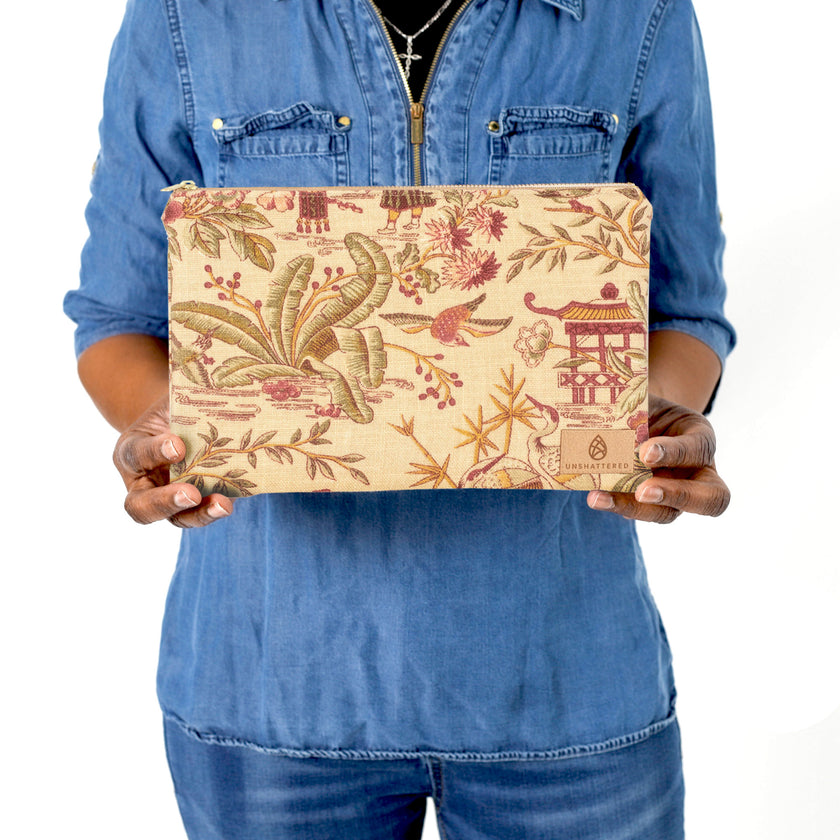 Person holding a large zip pouch with floral and architectural design