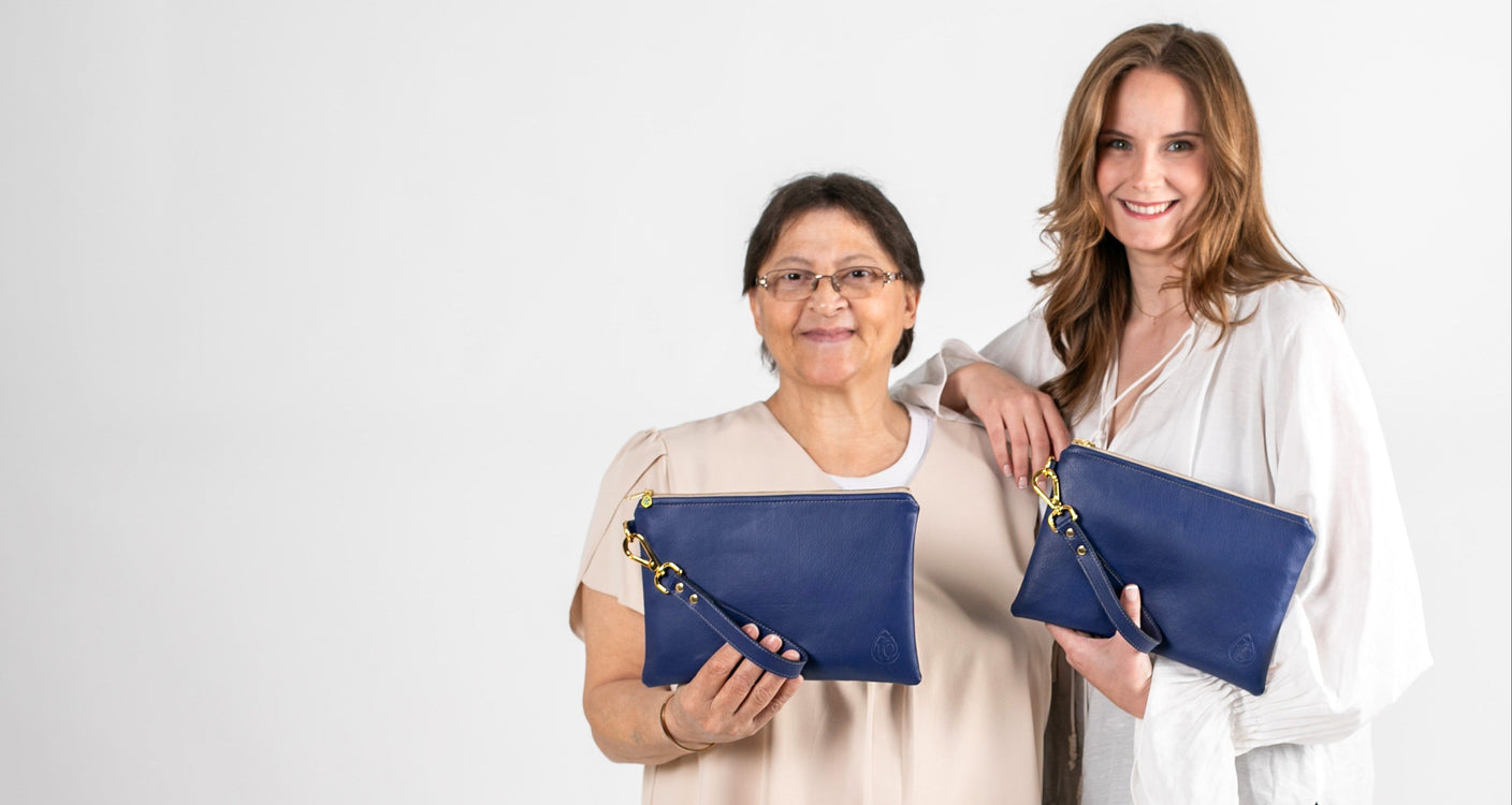 Two women holding blue clutch bags against a white background