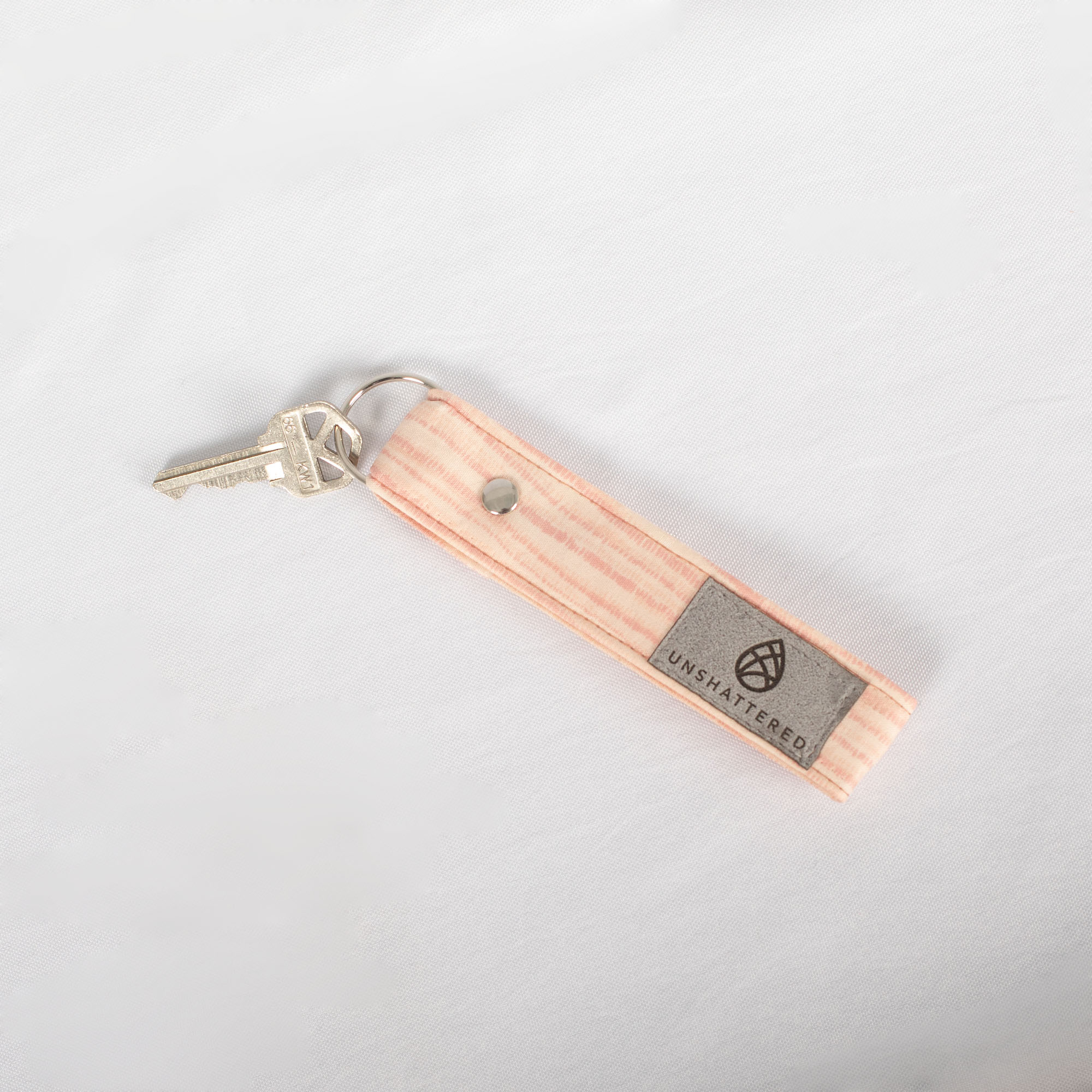 Loop Keychain with pink lines on it lays on a white cloth