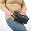 A woman holding a black toiletry kit made out of outdoor furniture material 