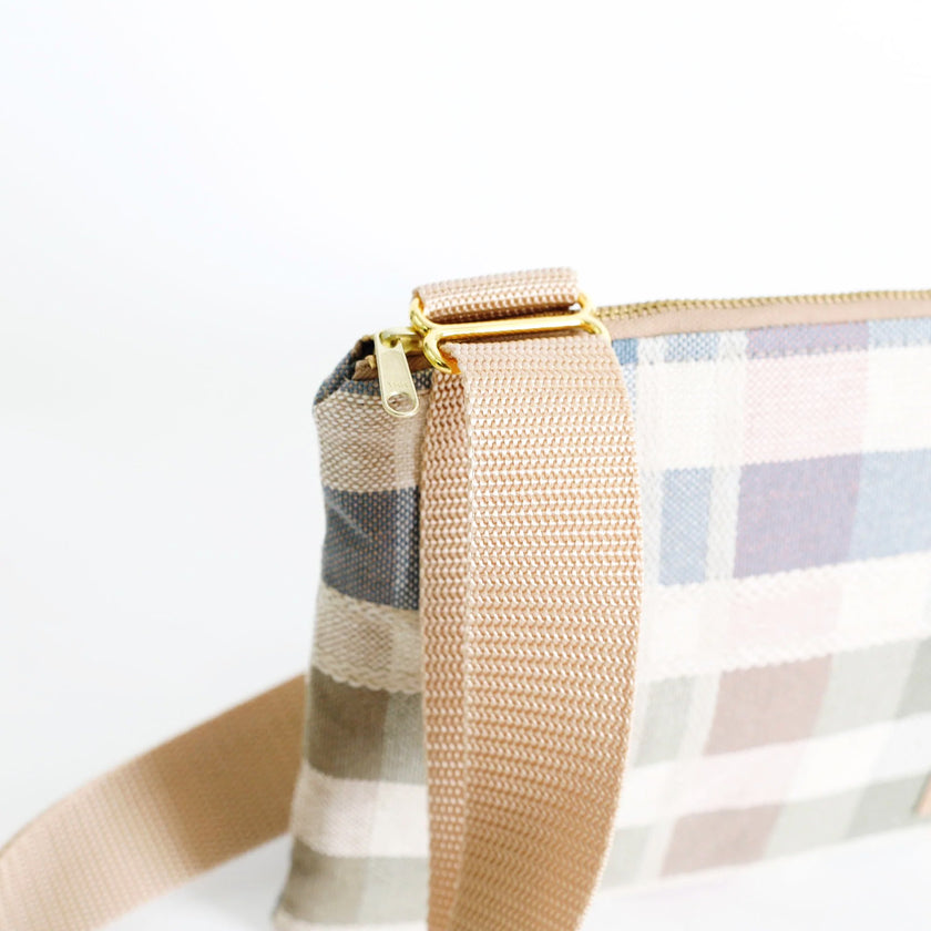 Close-up of a plaid bag with a beige strap on a white background
