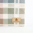 Plaid fabric with a 'Unshattered' logo on a light gray background