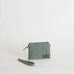 Green fabric pouch with a strap on a light gray background