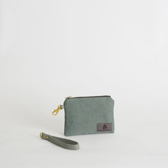 Green fabric pouch with a strap on a light gray background