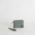 Green fabric pouch with a strap on a light gray background