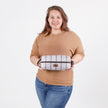Woman holding a purple and brown stripe toiletry kit against a white background
