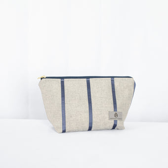 A makeup kit with a gray and blue striped exterior and a blue zipper closure, featuring gold-tone hardware.