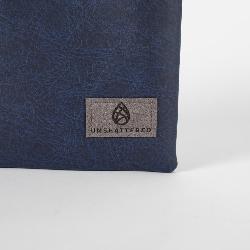 A detailed shot of a gray Unshattered label  in the bottom right corner of the zip pouch 