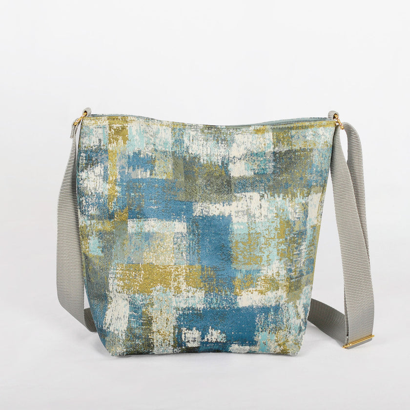 Back of a multi-color blue, green and white tote with a gray strap and gold-tone hardware
