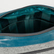 A green striped interior fabric with a gold seam on a gray wool errand bag with teal luxury leather alternative accents