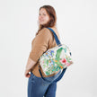 Woman carrying a floral-patterned convertible handbag on a white background