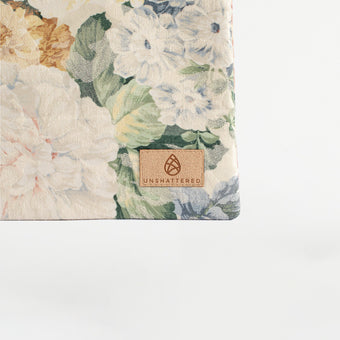 A tan label on a floral pattern large zip pouch named after Bella