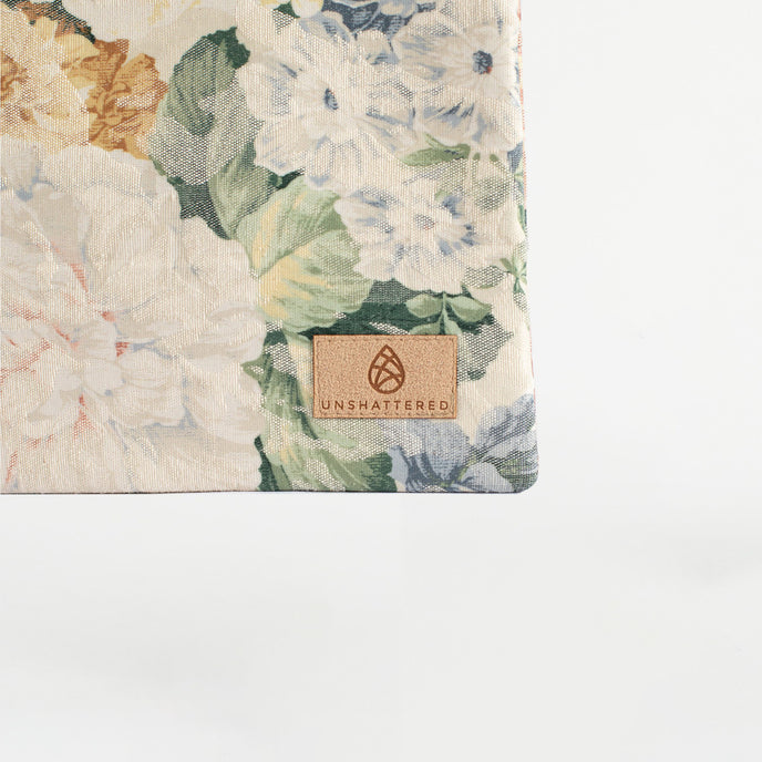 A tan label on a floral pattern large zip pouch named after Bella