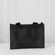 A black zippered shopper tote with two back pockets on the exterior with black hardware 