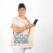 Woman holding a phone with a blue geometric-patterned bag on a white background