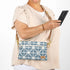 Woman holding a phone with a blue geometric-patterned bag on a white background named after Eric
