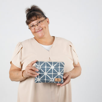 Person holding a blue geometric patterned pouch against a white background