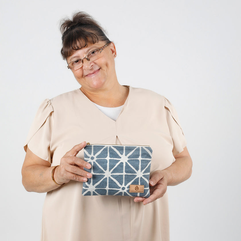 Person holding a blue geometric patterned pouch against a white background