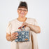 Woman holding a blue geometric-patterned pouch with cards against a white background