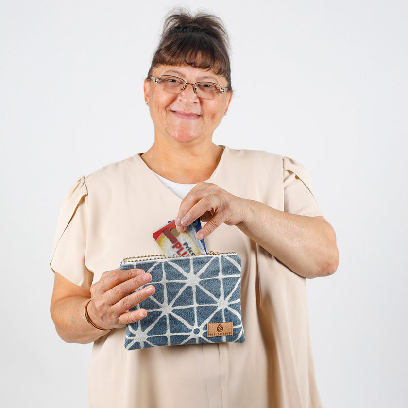 Woman holding a blue geometric-patterned pouch with cards against a white background