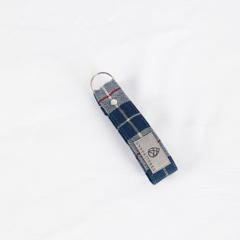 A vintage blue-grey plaid keychain with a silver-tone ring, handcrafted from 1955 Mercedes-Benz upholstery.