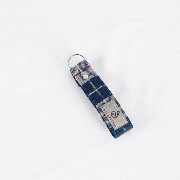 A vintage blue-grey plaid keychain with a silver-tone ring, handcrafted from 1955 Mercedes-Benz upholstery.