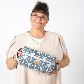 Woman holding a blue geometric-patterned bag against a white background