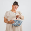 Lifestyle shot of woman pulling lip gloss out of makeup bag
