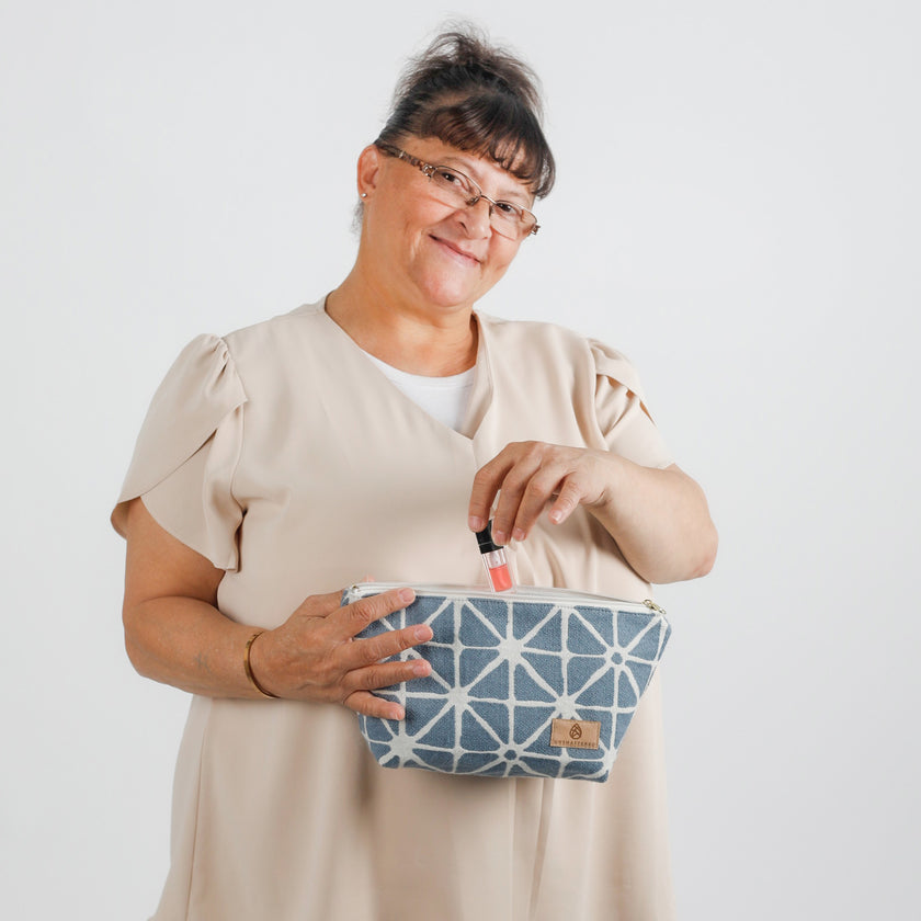 Lifestyle shot of woman pulling lip gloss out of makeup bag

