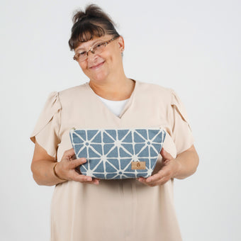 Person holding a blue geometric makeup pouch against a white background