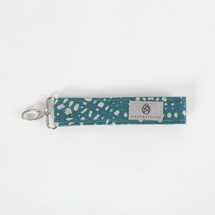 Bright and practical, this teal fabric wristlet key clip features a playful dotted pattern and sleek silver-tone hardware.