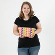 Woman holding a colorful geometric-patterned makeup  against a white background named after Brenda
