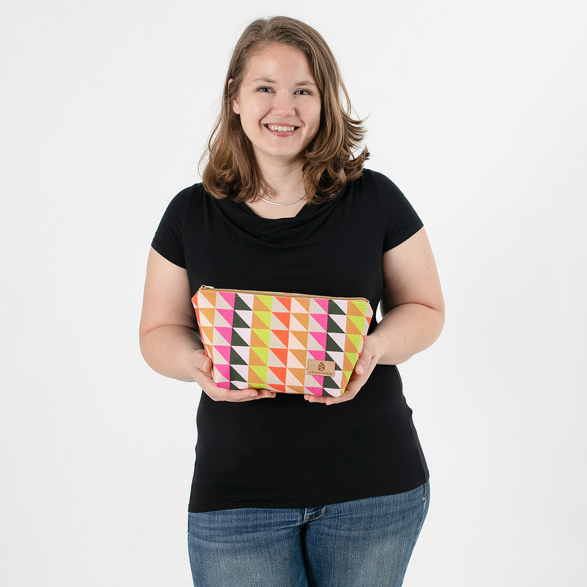 Woman holding a colorful geometric-patterned makeup  against a white background named after Brenda