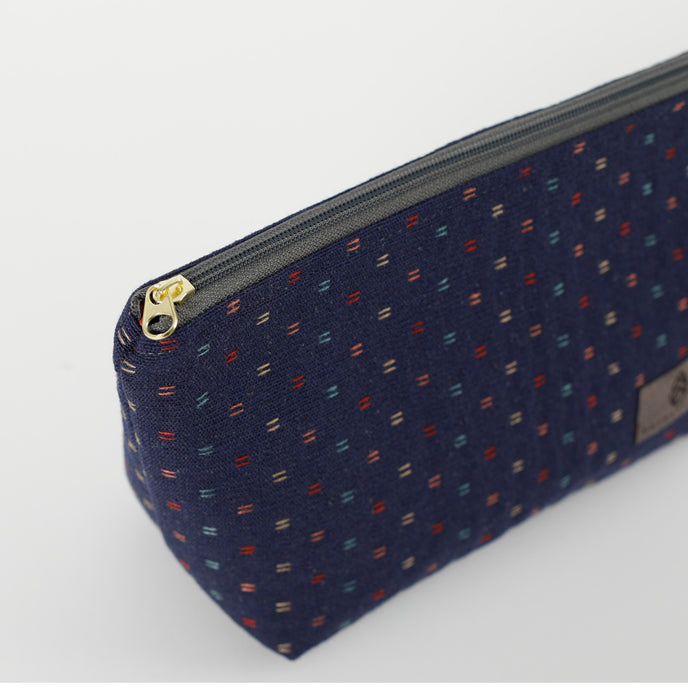 A gold tone zipper on a dark blue makeup kit with two lines fabric 