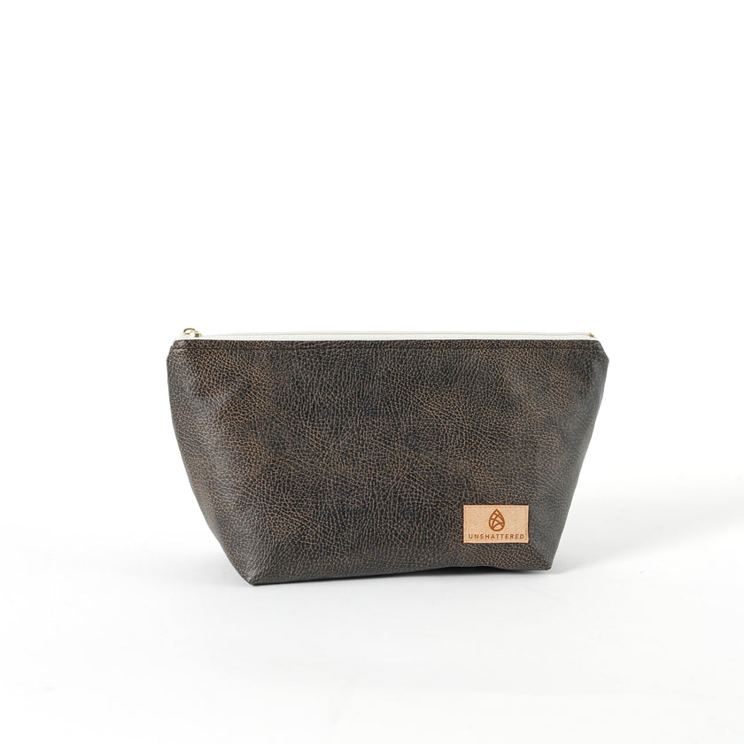 A brown makeup kit with a zip closure, made from industrial luxury leather alternative, displayed against a white background.