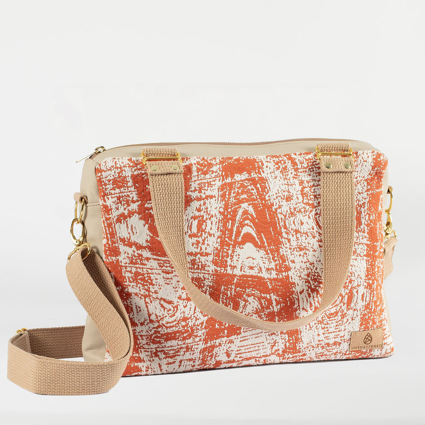 A burnt orange 'SWIZZLE' convertible handbag with tan cotton handle straps and an adjustable crossbody strap, displayed against a plain background.