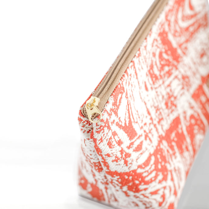 Orange and white marbled patterned makeup kit with a gold-tone zipper on a white background