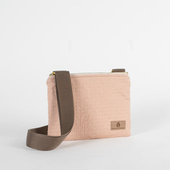 A pink and yellow dotted crossbody bag with a brown strap and tan Unshattered label 