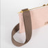 Detail shot of the gold hardware on a pink and yellow dotted crossbody pouch with a brown strap 