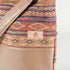 A tan label on a aztec design tote bag on top and brown luxury leather alternative on the bottom named after Chanel 